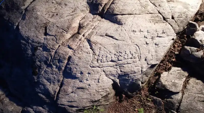 Representación detallada de una barca con 16 figuras y catorce "X" talladas a su lado.